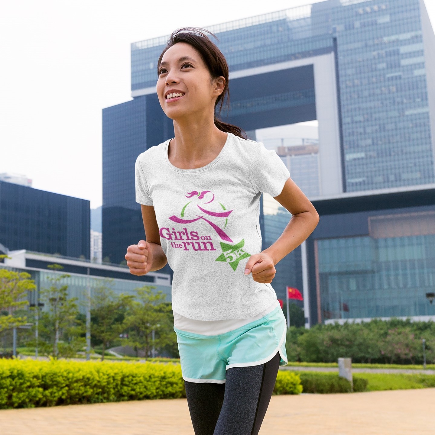Adult 5K participant smiles while running outdoors through the city